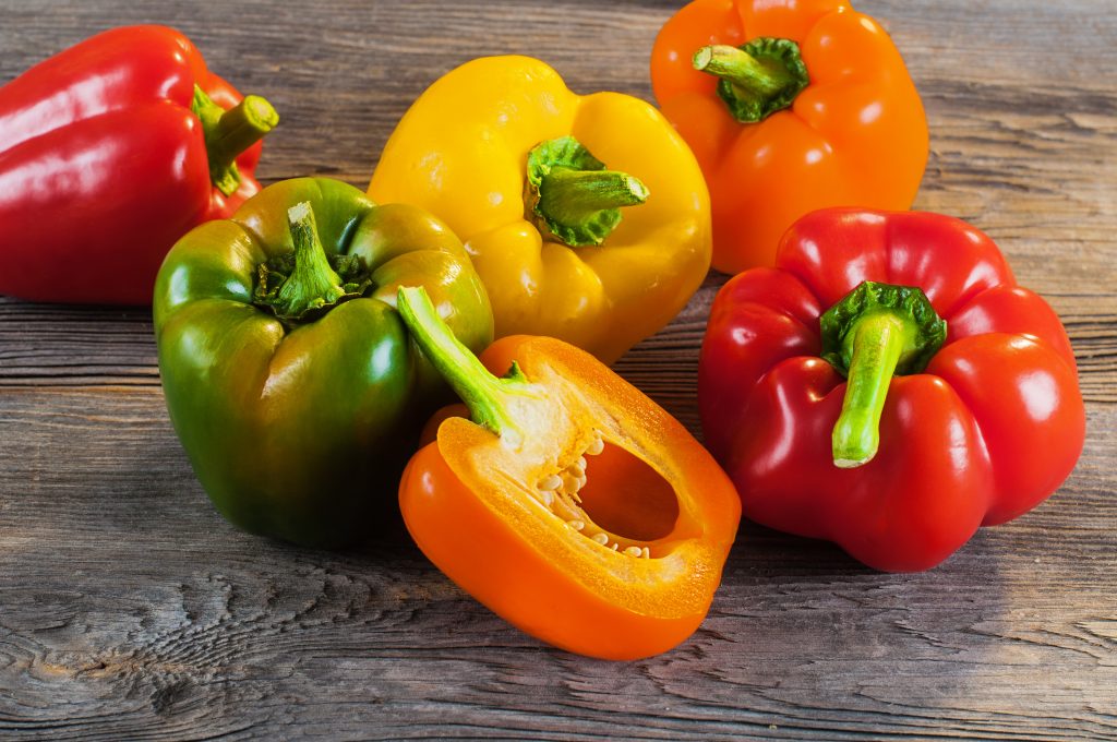 Fresh colored bell pepper on wooden background